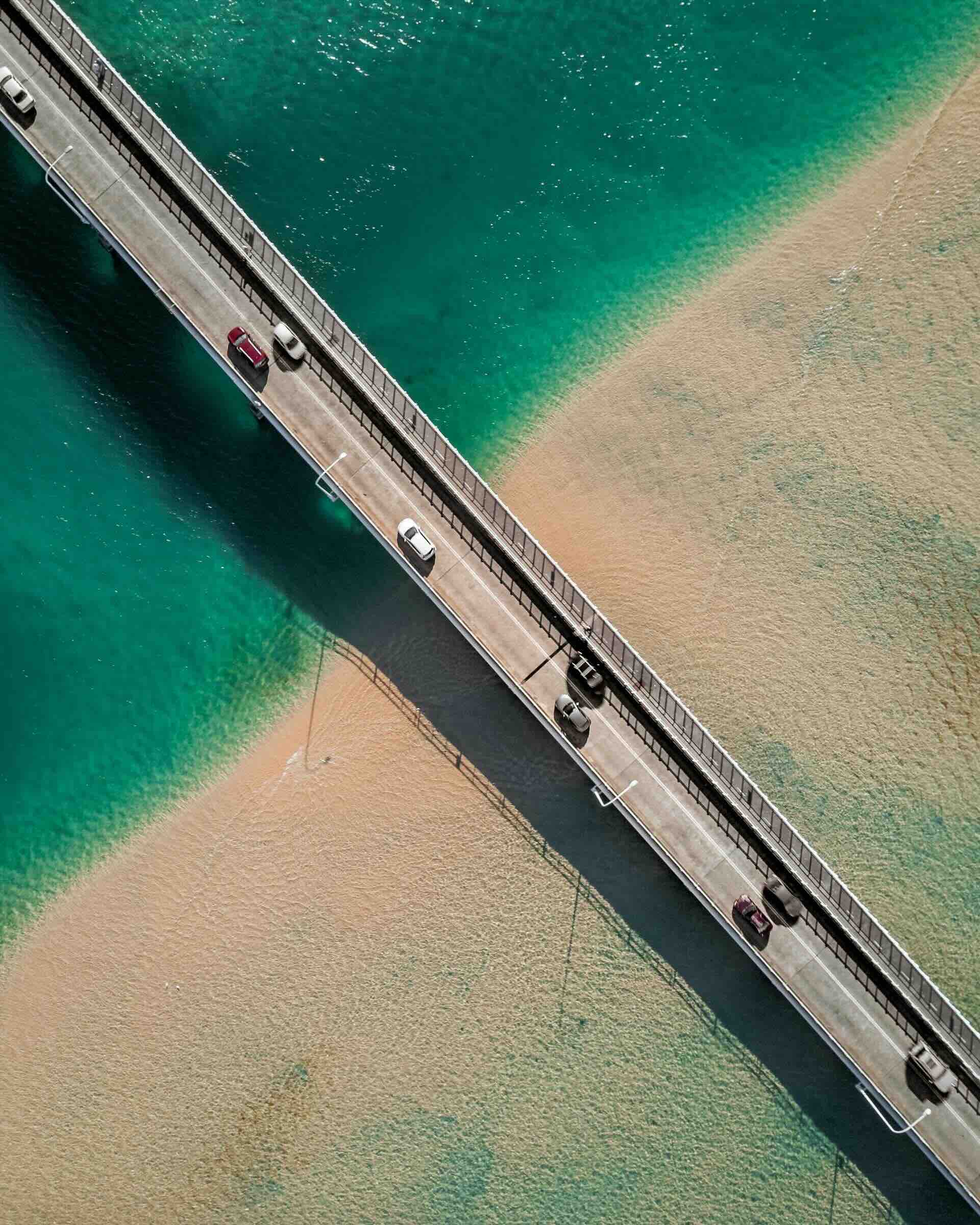 Road bridge over sparkling turquoise sea and beach in NSW, Australia.