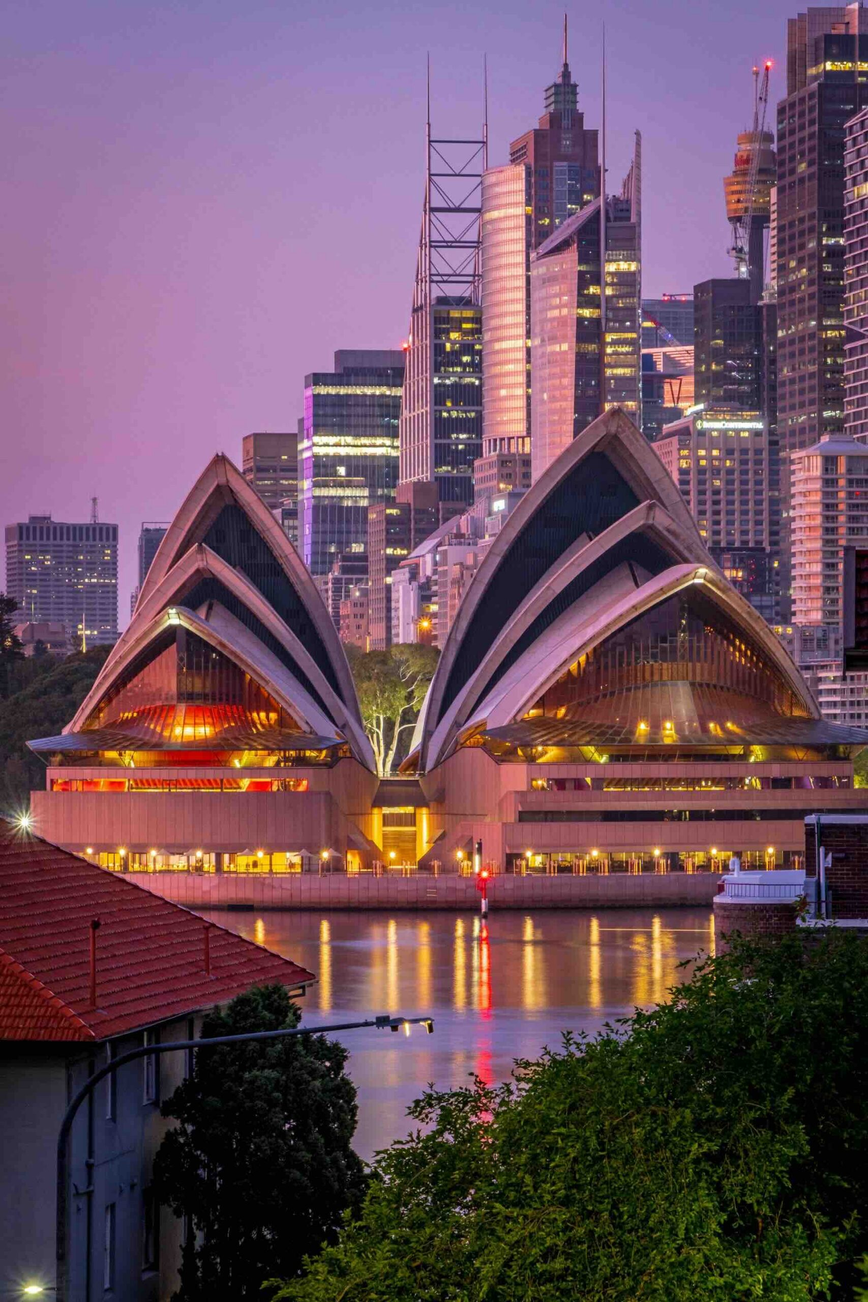 The Sydney Opera house at twilight with the city lights shining behind it.