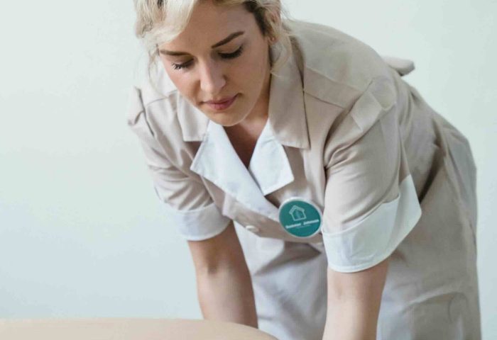 Care working dressed in uniform making a bed